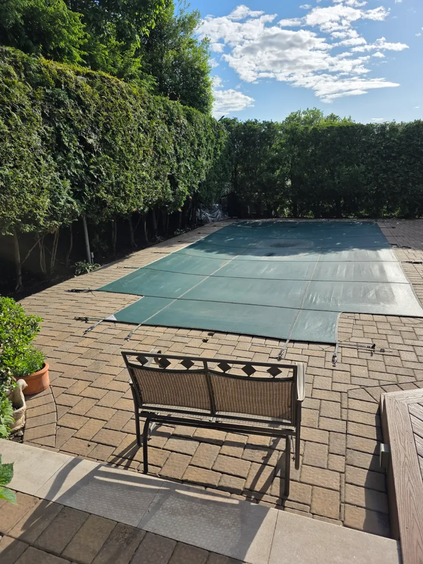 Covered pool and paver patio with a privacy hedge trimmed square