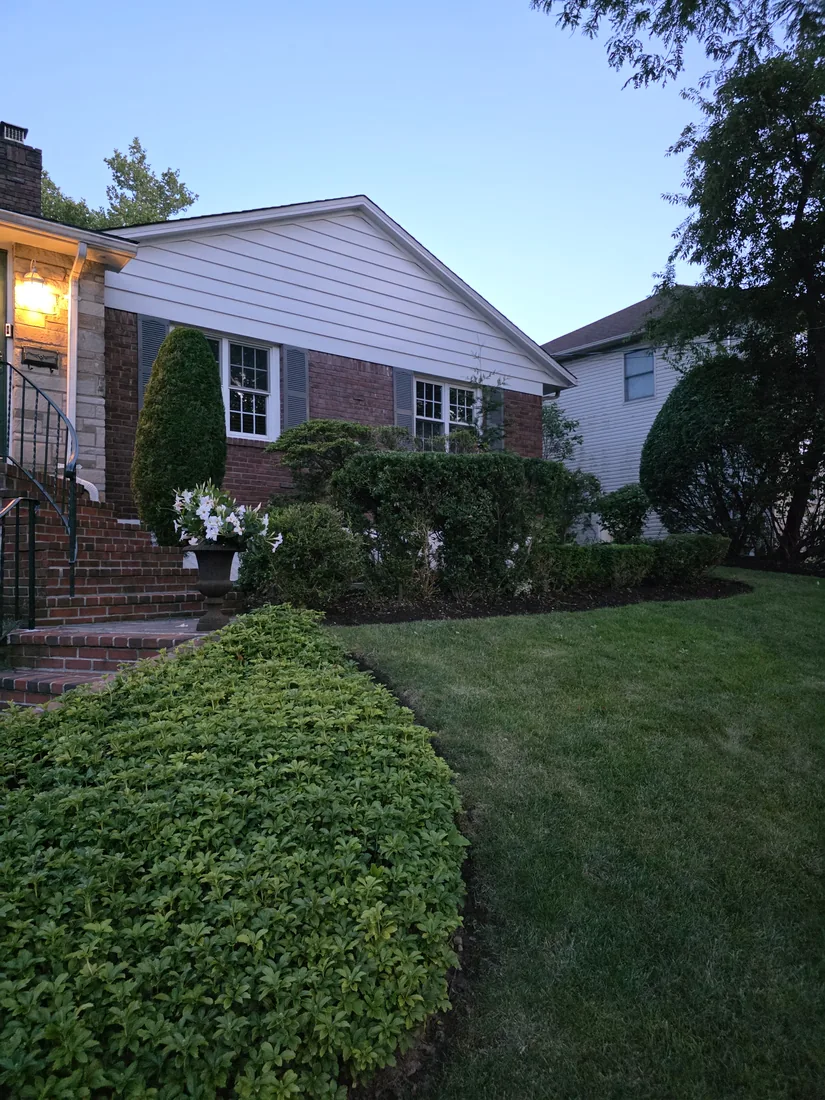 Brick home at dusk with recut front beds and shaped shrubs